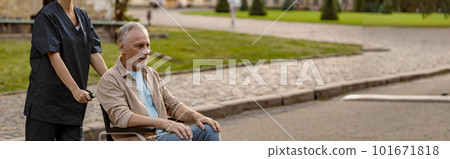 Full length shot of young nurse in protective face mask taking care of mature disabled man in wheelchair during a walk in the city Full length shot of young nurse in protective face mask taking care of mature disabled man in wheelchair during a walk in the city 101671818