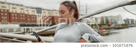 Young healthy sporty woman using cell phone during rest after jog standing on bridge Young healthy sporty woman using cell phone during rest after jog standing on bridge 101671876