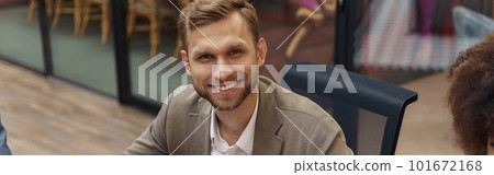 Smiling businessman sitting on meeting in modern office and looking at camera Smiling businessman sitting on meeting in modern office and looking at camera 101672168