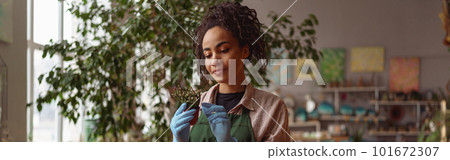 Young woman florist wearing apron taking care of plant in floral studio Young woman florist wearing apron taking care of plant in floral studio 101672307