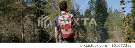 Back view on male tourist with backpack standing in forest on cliff. Trekking travel. Tourism. 101672352