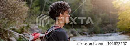 Side view on young Caucasian traveler with backpack standing in rural place at river. Side view on young Caucasian traveler with backpack standing in rural place at river. 101672367