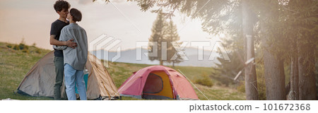 Young couple in love kissing at tents in camping site in mountains. Romantic tour. Young couple in love kissing at tents in camping site in mountains. Romantic tour. 101672368
