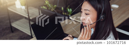 Young woman using headset and computer while talking with customers online Young woman using headset and computer while talking with customers online 101672716