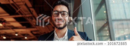 Indian businessman is making notes in notepad during working day in cafe and showing thumb up 101672885