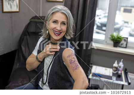 Long-haired woman looking at her new tattoo 101672913