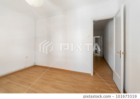 An empty small bright room with white walls and an open door overlooking a corridor in a spacious house. The concept of a room in a hotel or moving. Copyspace 101673319