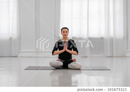 Healthy young woman doing padmasana lotus pose during yoga classes in a cozy bright room. The concept symbolizes purity and perfection with Buddhist meditation Healthy young woman doing padmasana lotus pose during yoga classes in a cozy bright room. The concept symbolizes purity and perfection with Buddhist meditation 101673321