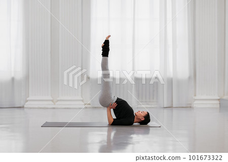 Professional instructor young woman does sarvangasana during a yoga class in a white light studio. The concept of getting rid of any ailment from allergies to nervous tension 101673322
