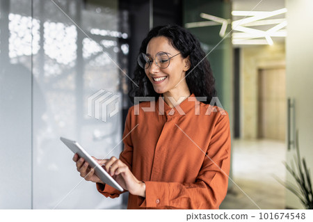 Indian female programmer standing inside the office with a tablet computer in her hands, the woman is testing a new software application. Indian female programmer standing inside the office with a tablet computer in her hands, the woman is testing a new software application. 101674548