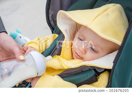 Serene scene of mother feeding her baby in a pram. 101676205