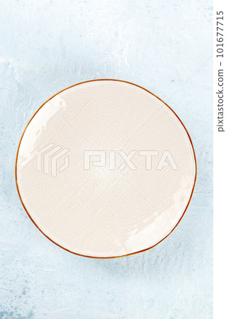 An empty white plate with a gold rim, top shot on a slate background 101677715