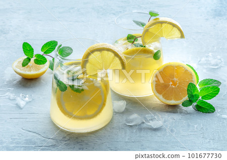 Lemonade with mint. Lemon water drink with ice. Two glasses and lemons Lemonade with mint. Lemon water drink with ice. Two glasses and lemons 101677730