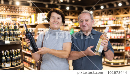 Elderly man and elderly woman choose bottle of alcohol 101678444