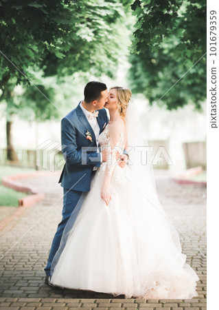 Beautiful young wedding couple posing with bouquet of flowers in hands Beautiful young wedding couple posing with bouquet of flowers in hands 101679359