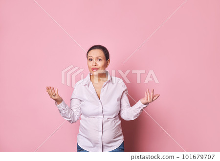 Beautiful middle aged pregnant woman asks questions, looking perplexed, expressing misunderstanding and astonishment, posing with hands palms up on pink isolated background. Pregnancy. Maternity leave Beautiful middle aged pregnant woman asks questions, looking perplexed, expressing misunderstanding and astonishment, posing with hands palms up on pink isolated background. Pregnancy. Maternity leave 101679707