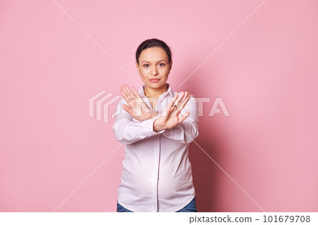 Middle aged confident pregnant woman standing with outstretched hand showing stop sign, crossing arms, looking at camera, preventing you, expressing denial and refusal over isolated pink background Middle aged confident pregnant woman standing with outstretched hand showing stop sign, crossing arms, looking at camera, preventing you, expressing denial and refusal over isolated pink background 101679708