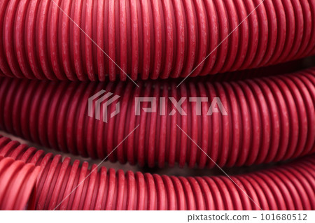 Corrugated for insulation cable of wires underground, plastic tube, electricity protection pipe for construction works, red corrugation close-up with copy space. High quality photo Corrugated for insulation cable of wires underground, plastic tube, electricity protection pipe for construction works, red corrugation close-up with copy space. High quality photo 101680512