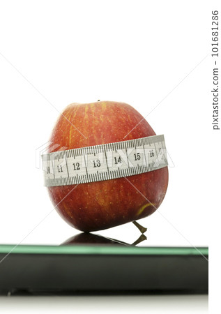 Apple wrapped with measuring tape on a scale Apple wrapped with measuring tape on a scale 101681286
