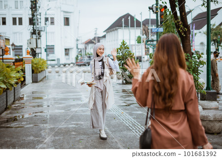 female traveller with hijab waving her hand to her friend female traveller with hijab waving her hand to her friend 101681392