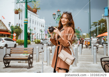 asian traveller in brown coat holding the camera asian traveller in brown coat holding the camera 101681429