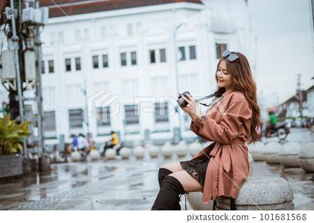 female traveller checking the photo result while sitting on the stone seat female traveller checking the photo result while sitting on the stone seat 101681568