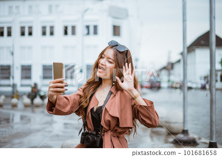 female traveller waving her hand and looking at her phone female traveller waving her hand and looking at her phone 101681658