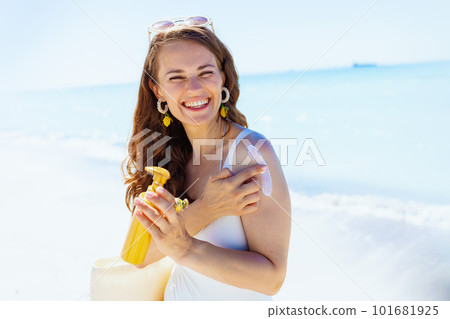 Portrait of smiling stylish woman at beach applying spf Portrait of smiling stylish woman at beach applying spf 101681925