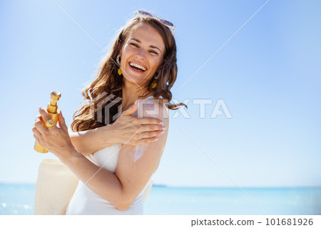 smiling elegant female in white swimwear at beach 101681926