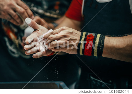 male powerlifter applying gym chalk on his hands before bench press powerlifting competition 101682044