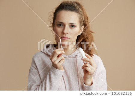 woman applying ointment using cotton swab against beige 101682136