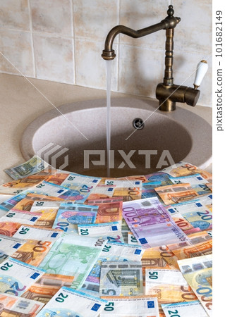 A lot of money lying in front of the sink where the water leaks from the bronze faucet.  101682149
