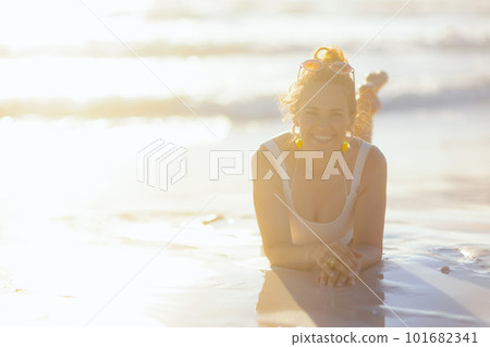 smiling elegant female in white swimwear laying at beach smiling elegant female in white swimwear laying at beach 101682341