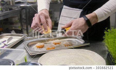 Male cook grates cheese on baked sweet potato Male cook grates cheese on baked sweet potato 101682521