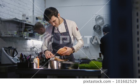 Adult cook in apron cleans up working desk Adult cook in apron cleans up working desk 101682529