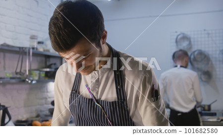 Professional chef stands by kitchen table and making food Professional chef stands by kitchen table and making food 101682580