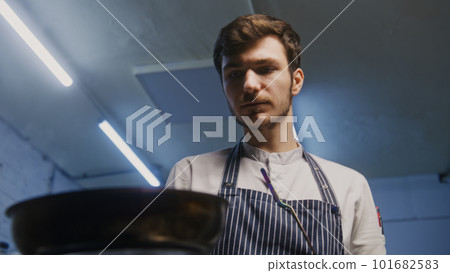 Male cook fries and stirs meat in frying pan Male cook fries and stirs meat in frying pan 101682583