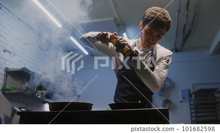 Male cook adds spices using spice grinder 101682598