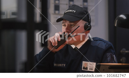 Busy security worker talks with coworker by walkie talkie Busy security worker talks with coworker by walkie talkie 101682747