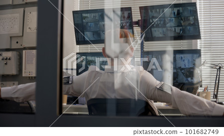 Security officer controls CCTV cameras and leans back 101682749