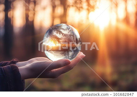 Woman's hand holding a crystal ball reflecting nature 101682847