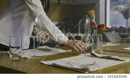 Waitress in uniform set the tables by wine glasses Waitress in uniform set the tables by wine glasses 101683040
