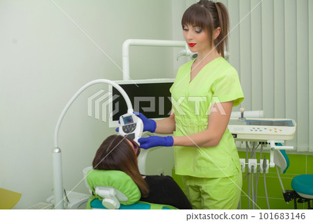 Woman sitting in dental chair at medical center while professional doctor fixing her teeth 101683146