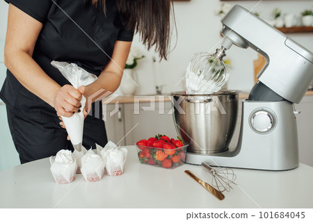 The girl cook puts the cream from the mixer into the mold for decorating cakes 101684045