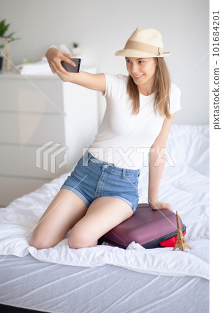 Attractive girl sitting on sofa and packing luggage Attractive girl sitting on sofa and packing luggage 101684201