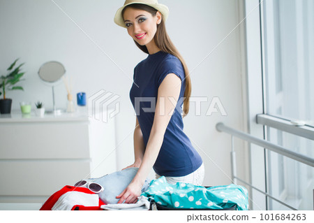 Attractive girl sitting on sofa and packing luggage 101684263