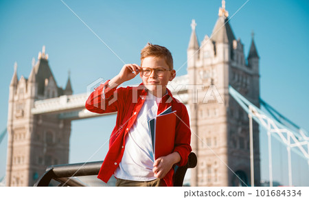 Student with backpack and books. Happy confident pupil ready for education in England. Portrait of boy with Tower bridge on background. Kid in glasses. English language courses 101684334