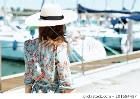 Seen from behind elegant traveller woman in floral dress on pier Seen from behind elegant traveller woman in floral dress on pier 101684487