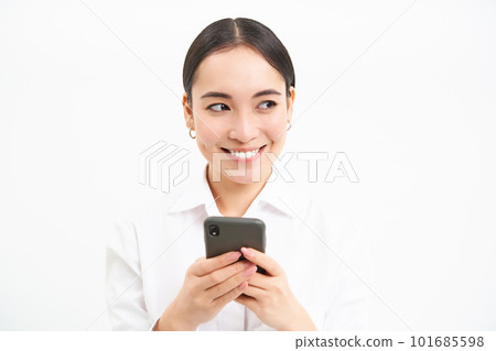 Business and corporate people. Young asian female entrepreneur, looking at smartphone, working on mobile phone, standing over white background Business and corporate people. Young asian female entrepreneur, looking at smartphone, working on mobile phone, standing over white background 101685598