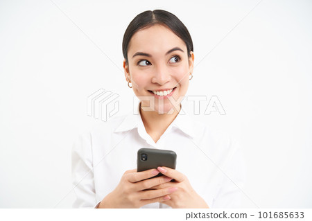 Image of asian saleswoman, office manager holding smartphone, working on text for social media, using cellphone, white background 101685633